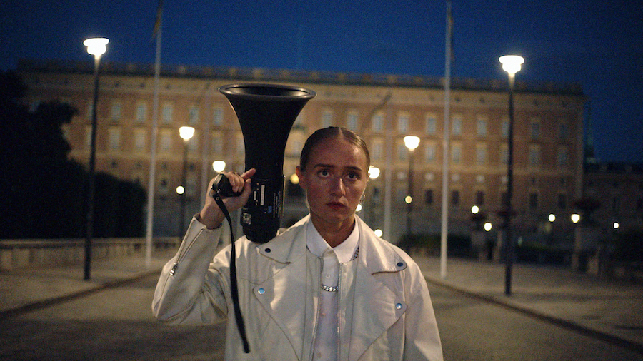 Silvana Imam med megafon utanför kungliga slottet i Stockholm.