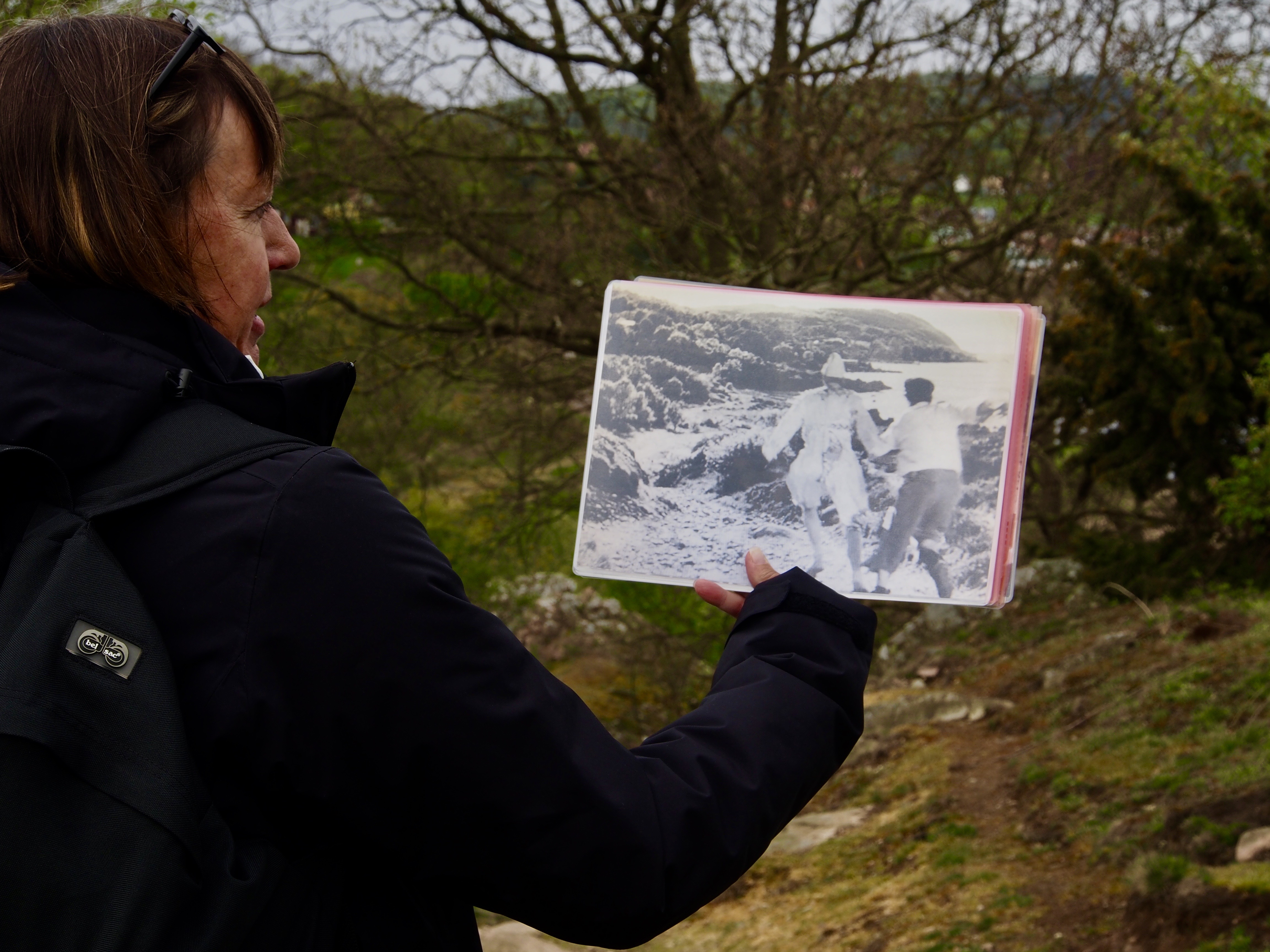 En kvinna håller upp en svartvit bild från Bergmanfilm vid inspelningsplatsen.