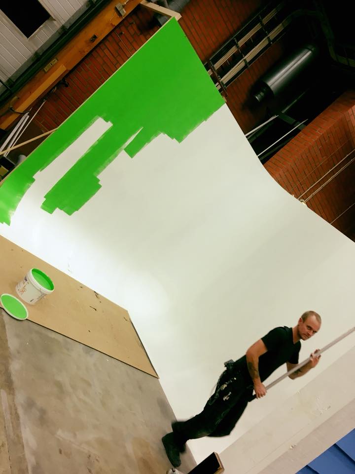 En man målar en vägg i strakt grön färg.